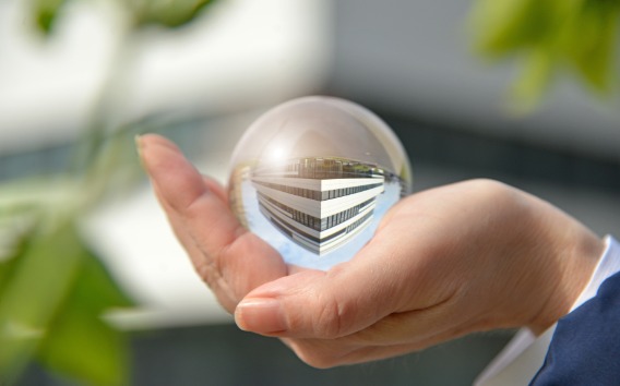 Mano sosteniendo una bola de cristal que refleja un edificio Grünenthal de nuestro Campus en Aquisgrán, Alemania.